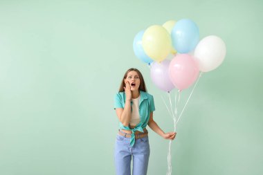 Renkli balonları olan şaşırmış genç bir kadın.