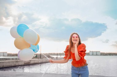 Nehir kenarında balonlu genç bir kadın.