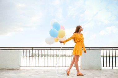 Nehir kenarında balonlu genç bir kadın.