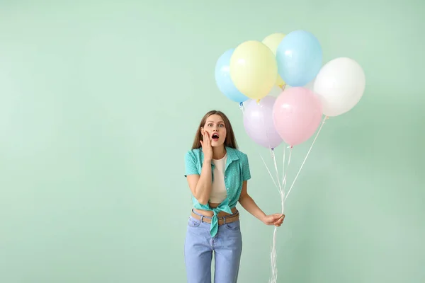 色の背景に風船と驚きの若い女性 — ストック写真