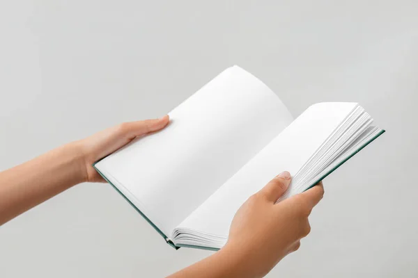 Hands with open book on light background