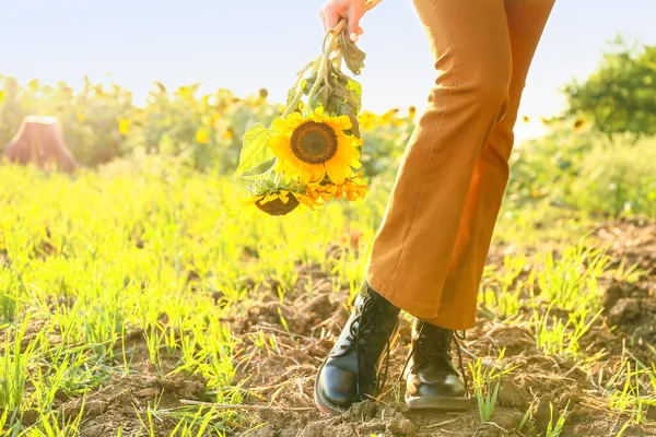 Beautiful young woman with bouquet of sunflowers in field