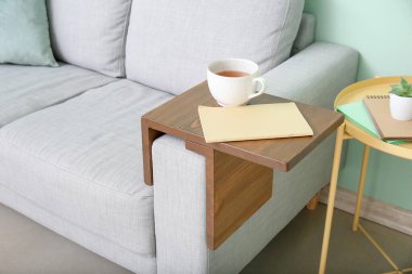 Bir fincan çay, odadaki dizlik masasında defter var.