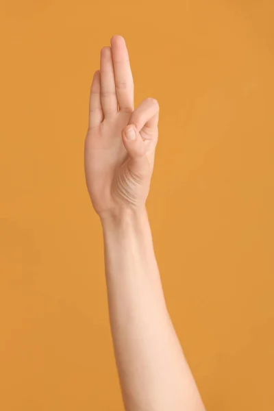 Hand showing letter F on color background. Sign language alphabet