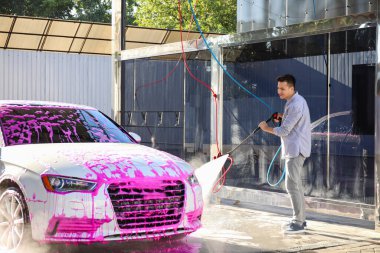 Adam dışarıda arabasını yıkıyor.