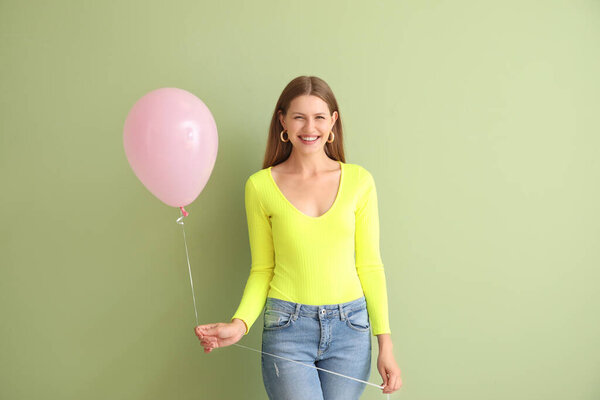 Young woman with balloon on color background