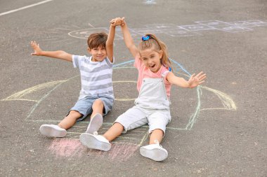 Dışarıdaki roketin tebeşiri üzerinde oturan küçük çocuklar.