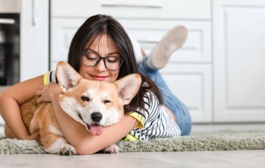 Mutfakta tatlı Corgi köpeği olan bir kadın var.