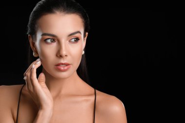 Koyu arkaplanda güzel göz farı olan genç bir kadın.