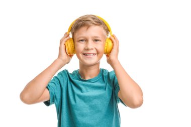 Küçük çocuk beyaz arka planda müzik dinliyor.