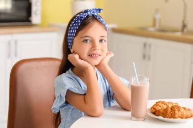 Küçük kız evde lezzetli çikolatalı süt içiyor.