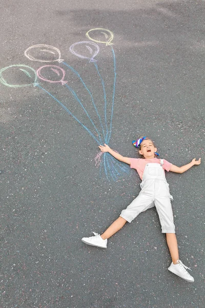 Kleines Mädchen Liegt Neben Kreidezeichnung Von Luftballons Auf Asphalt — Stockfoto