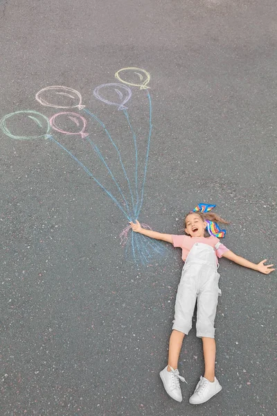Kleines Mädchen Liegt Neben Kreidezeichnung Von Luftballons Auf Asphalt — Stockfoto