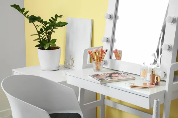 Table with mirror and makeup cosmetics in modern dressing room