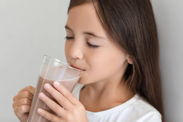 小女孩在浅色背景下喝着美味的巧克力牛奶 — 图库照片