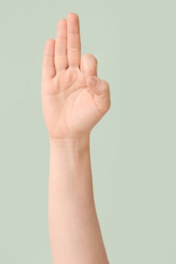 Renk arkaplanında F harfi görünüyor. İşaret dili alfabesi