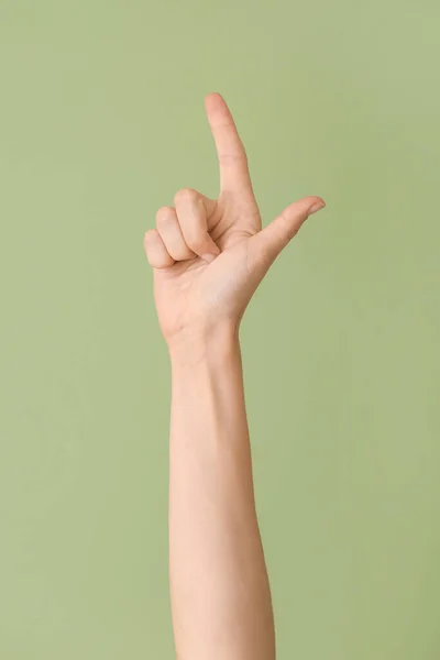 Hand showing letter L on color background. Sign language alphabet