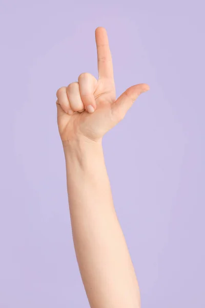 Hand showing letter L on color background. Sign language alphabet