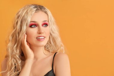 Renkli arka planda güzel göz farları olan genç bir kadın.