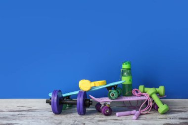 Renkli duvarın yanında spor aletleri var.