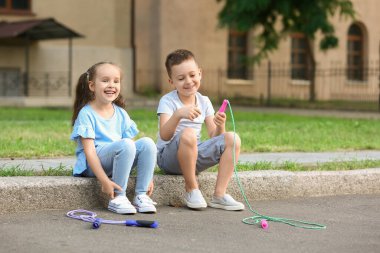 Dışarıda ip atlayan şirin çocuklar.