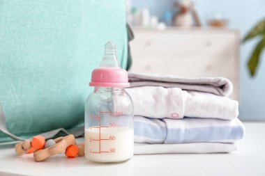 Elbiseli ve çantalı bebek için bir şişe süt.