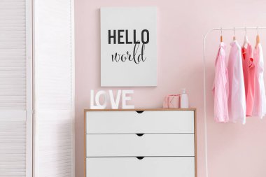 Soyunma odasındaki renkli duvarın yanında elbise askısı olan modern çekmeceler.