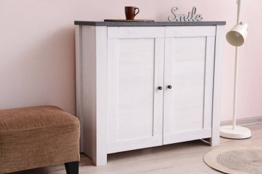 Odada renkli duvarın yanında lamba ve kanepe olan modern çekmeceler.