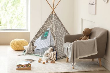 Çağdaş çocuk odasının içinde oyun çadırı ve oyuncaklar var.