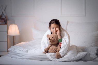 Yatak odasında uyku bozukluğu çeken küçük bir kız.