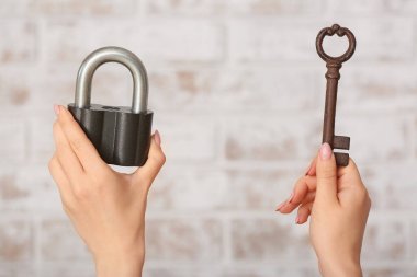 Anahtarı olan kadın eller ve arka planda asma kilit
