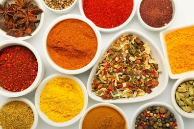 Beyaz arka planda farklı aromatik baharatlar bulunan kaseler