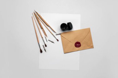 Beyaz arkaplanda yazı çalışması için zarf ve malzeme içeren bir kağıt.