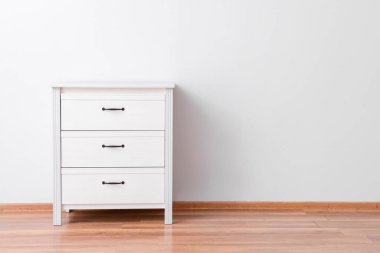 Çekmecelerin modern sandığı, odanın ışık duvarının yanında.