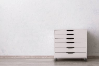 Çekmecelerin modern sandığı, odanın ışık duvarının yanında.