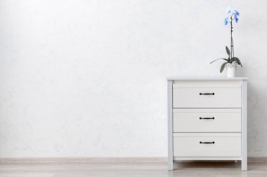 Çekmecelerin modern sandığı, odanın ışık duvarının yanında.