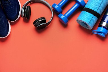 Spor ayakkabılar, bir şişe su, yoga minderi, halterler ve kulaklıklar.