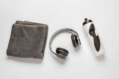 Havlu, su şişesi ve beyaz arka planda kulaklık.