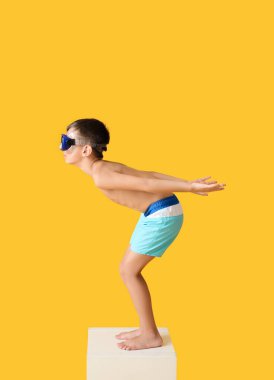 Yüzme bloğunda başlangıç pozisyonundaki küçük çocuk renk arkaplanına karşı