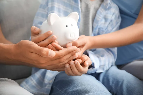Family with piggy bank at home, closeup