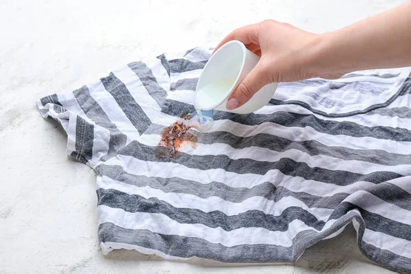 Woman removing stain from clothes on white background