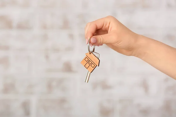 Female hand with key from house on light background