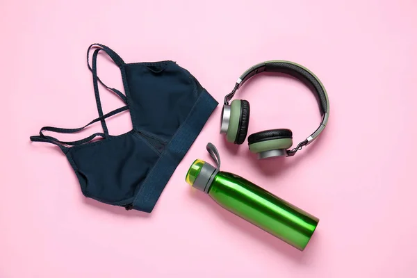 Sportive clothes, bottle of water and headphones on color background