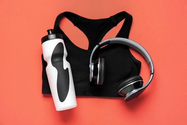 Sportive clothes, bottle of water and headphones on color background