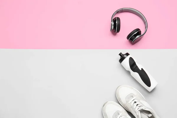 Sportive shoes, bottle of water and headphones on color background