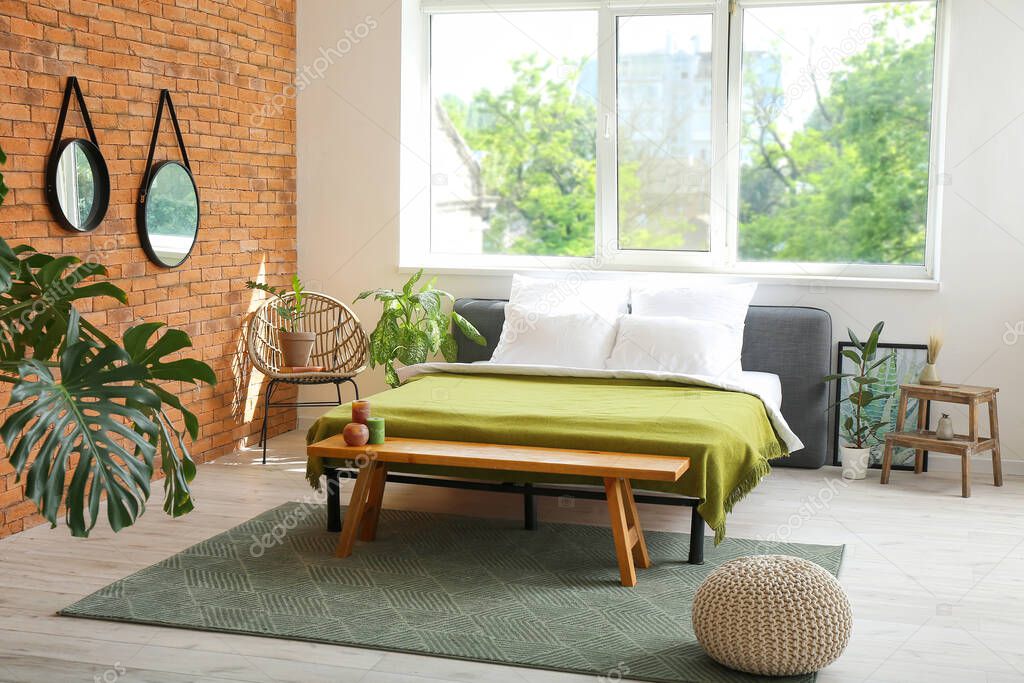 Stylish interior of modern bedroom with mirrors and houseplants