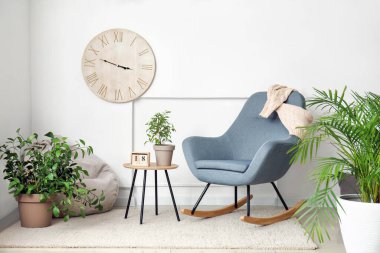 Beyaz duvarın yanında şık koltukları ve çiçekleri olan bir oda.