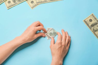 Origami balıklı kadın eller. Renkli arka planda dolar banknotundan yapılmış.
