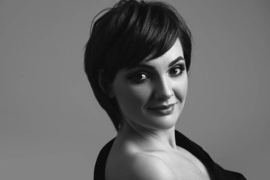 Siyah beyaz portre. Siyah arka planda kısa saçlı güzel bir kadın.