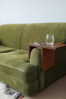 Odadaki koltukaltı masasında cep telefonu olan bir bardak su.